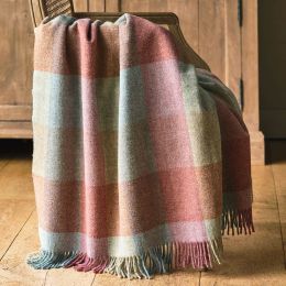 checked wool throw in shades of pale pink, blue and green draped over a wooden chair