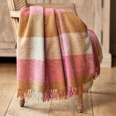 checked wool throw in shades of pink and orange draped over a wooden chair