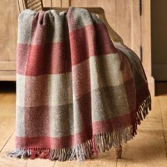 Checked wool throw in shades of red and grey draped over a chair
