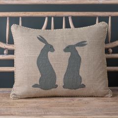 Linen cushion with two sitting hares appliqued in charcoal fabric. 