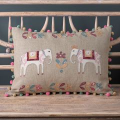 linen cushion with two applique elephants, floral motif and a colourful pompom trim in blue pink and safrron. 